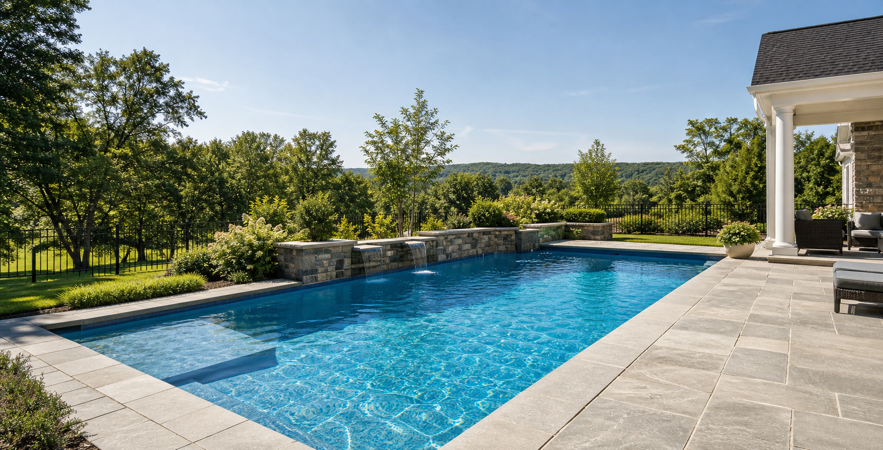 A bright residential inground pool with stone patio and green Hudson Valley hills